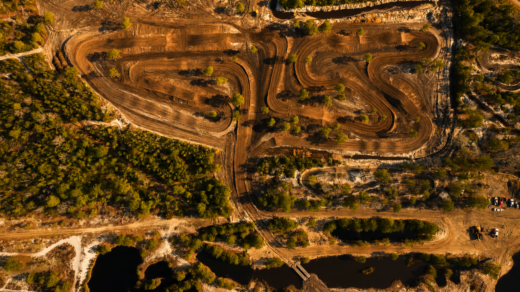 Aerial view of a freshly cut motocross track beside a river